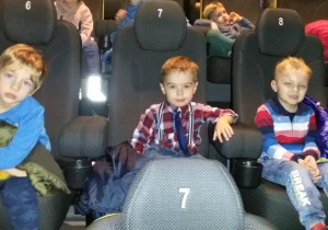 Widok na trzech chłopców siedzących na widowni kinowej.